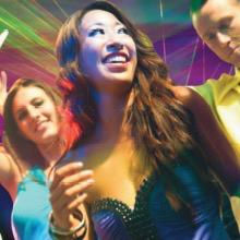 Blurred image of people in a vibrant, colorful setting, suggesting a party or celebration atmosphere.