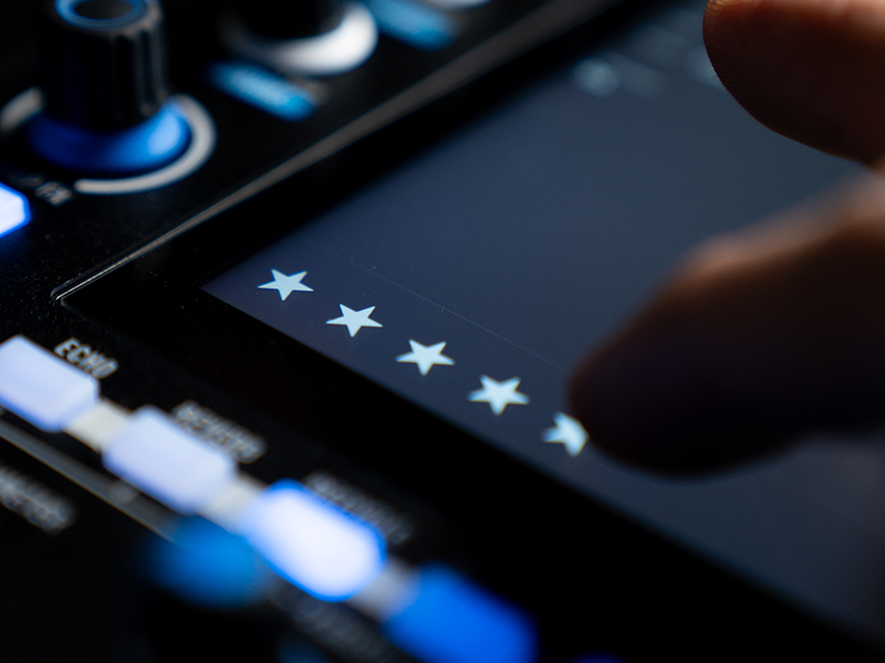 Close-up of a dark surface with four white stars arranged horizontally, illuminated controls visible, blue lighting in background.