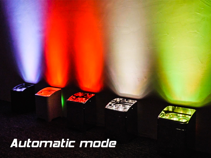 Stage lighting setup showing different colored beams - purple, red, white, and green - in automatic mode with control units visible below.