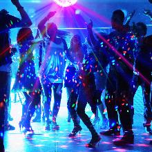 Colorful dance floor with silhouettes of people dancing under blue and purple lights, creating a vibrant nightclub atmosphere.