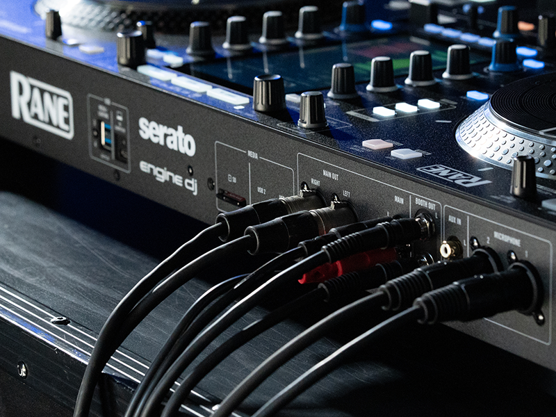 Text reads 'KADE'. Professional DJ mixer console with multiple faders, knobs, and audio input connections shown in close-up detail with blue accent lighting.