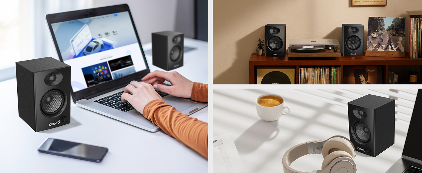 Desktop setup showing studio monitors/speakers in black, with laptop and mobile device. Person working at desk with audio equipment arranged on shelving in background.