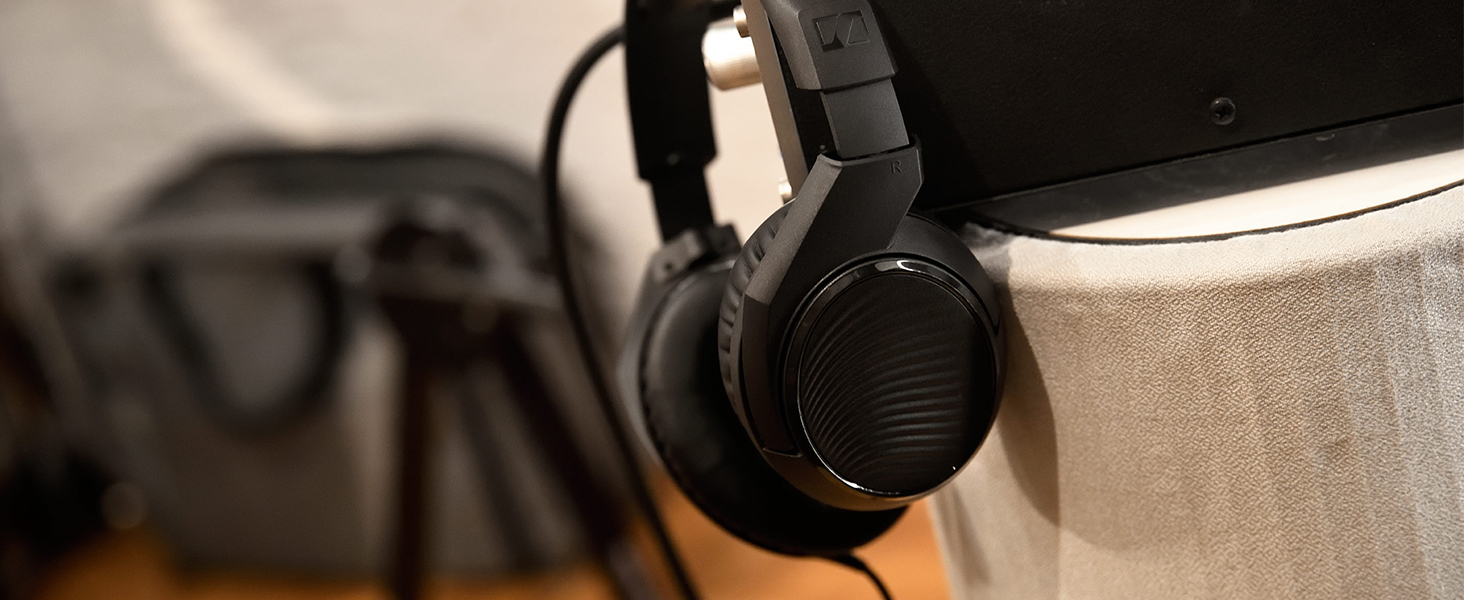 Side view of black over-ear headphones next to a light-colored container against dark background.