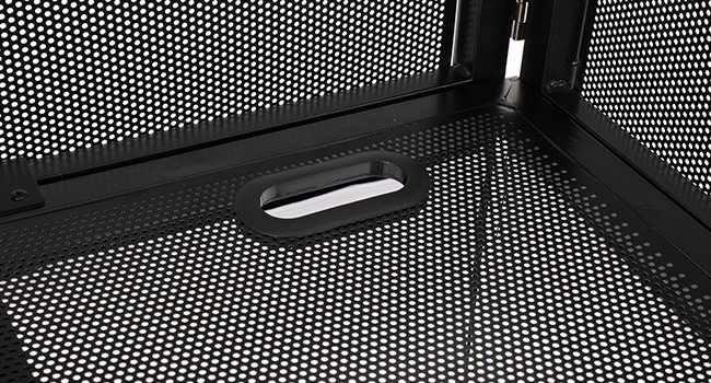 Close-up of a black perforated metal surface with a small white object, possibly a handle or latch, visible in the corner.